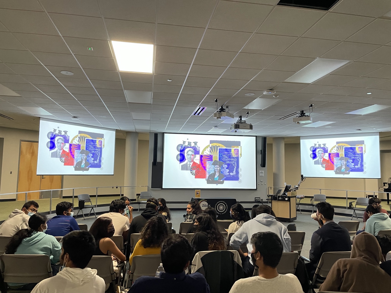 Students seated in a lecture hall at Michigan State University facing three projection screens